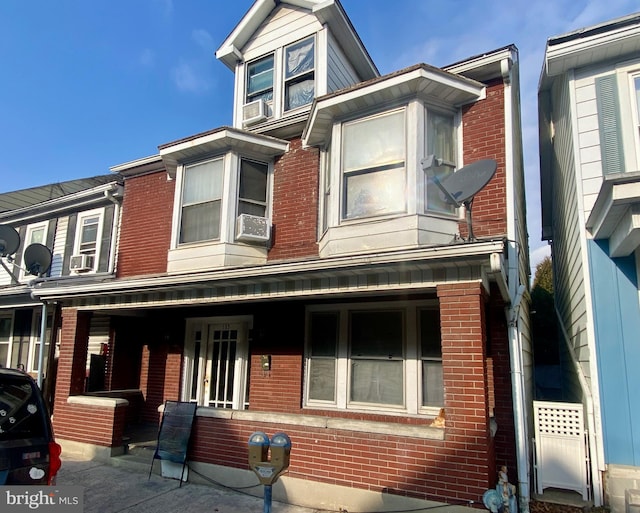 view of property featuring brick siding and a porch