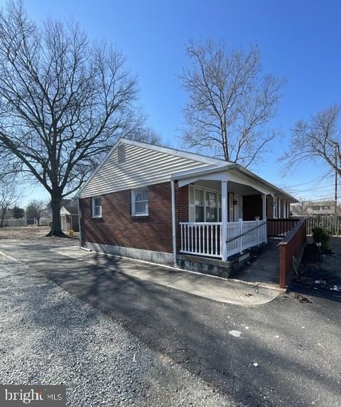 view of side of property with driveway, a porch, and brick siding