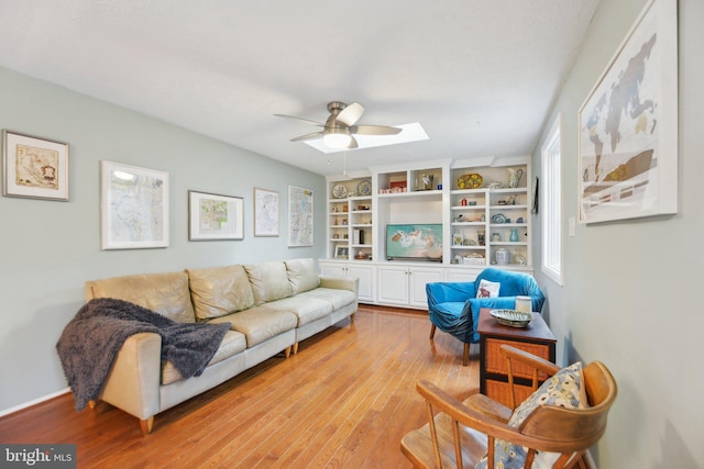 living area with built in features, light wood-style flooring, and a ceiling fan