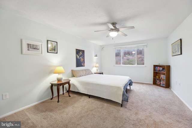 carpeted bedroom with a textured ceiling, a ceiling fan, and baseboards