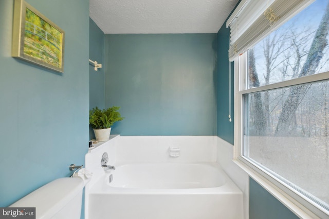 full bath with a bath, toilet, and a textured ceiling