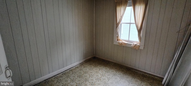 unfurnished room featuring baseboards and wooden walls