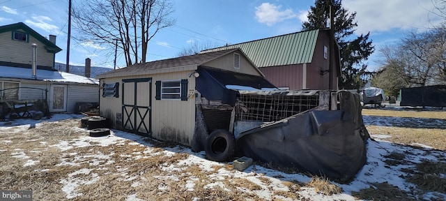 view of snow covered exterior featuring an outbuilding and metal roof