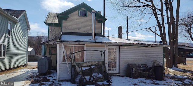 snow covered back of property featuring heating fuel