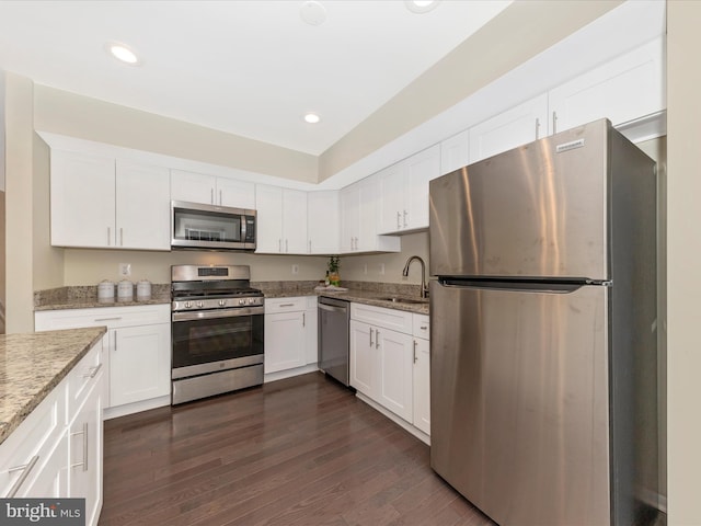 kitchen with appliances with stainless steel finishes, white cabinetry, a sink, and dark wood-style floors