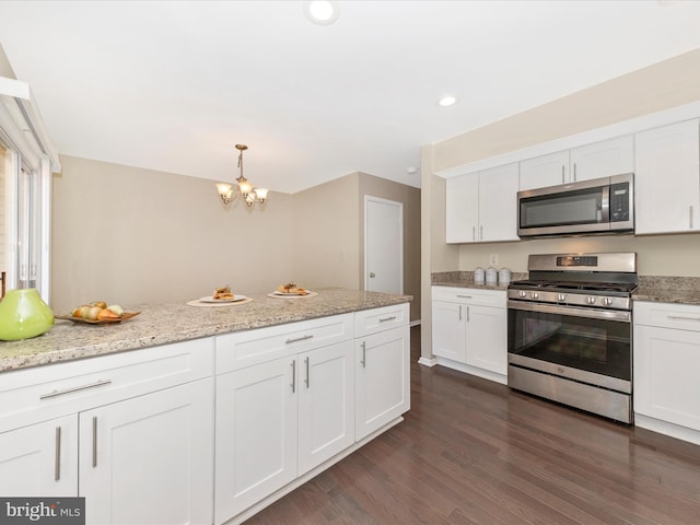 kitchen with stainless steel appliances, white cabinetry, dark wood finished floors, and light stone countertops