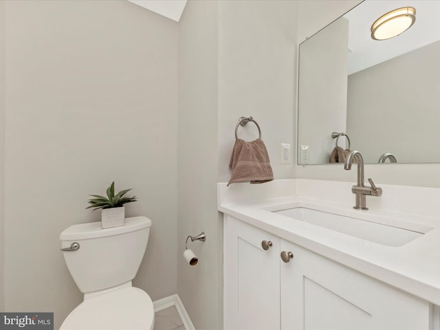 half bath with toilet, baseboards, and vanity