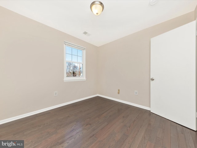 unfurnished room with dark wood-type flooring, visible vents, and baseboards