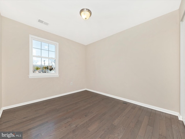 spare room featuring visible vents, baseboards, and dark wood-style flooring