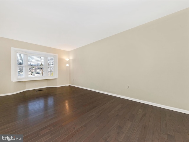 empty room with dark wood finished floors and baseboards