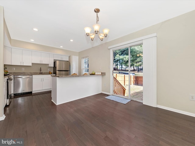 kitchen with a chandelier, stainless steel appliances, a peninsula, white cabinets, and dark wood-style floors