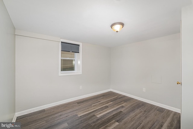 unfurnished room featuring dark wood-style flooring and baseboards