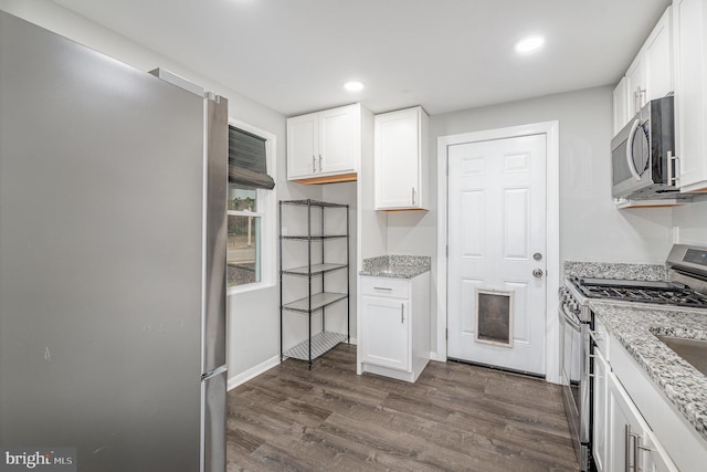 kitchen with appliances with stainless steel finishes, dark wood-style flooring, and white cabinets