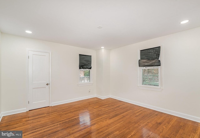 empty room with baseboards, wood finished floors, and recessed lighting