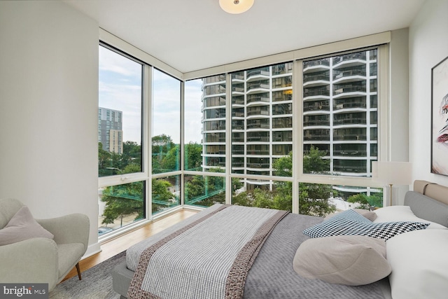 bedroom featuring a city view, a wall of windows, and wood finished floors