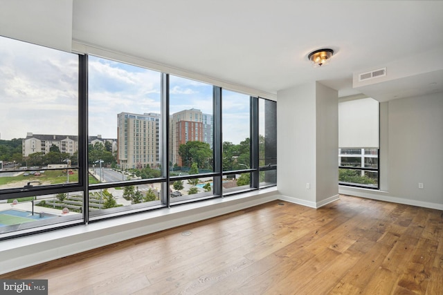 spare room with baseboards, wood-type flooring, visible vents, and a city view