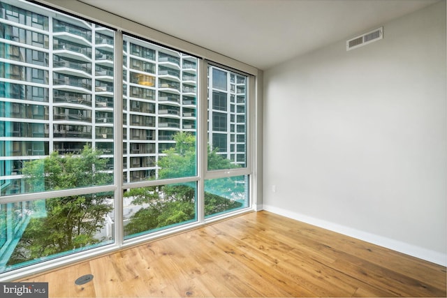 empty room with wood finished floors, visible vents, and baseboards