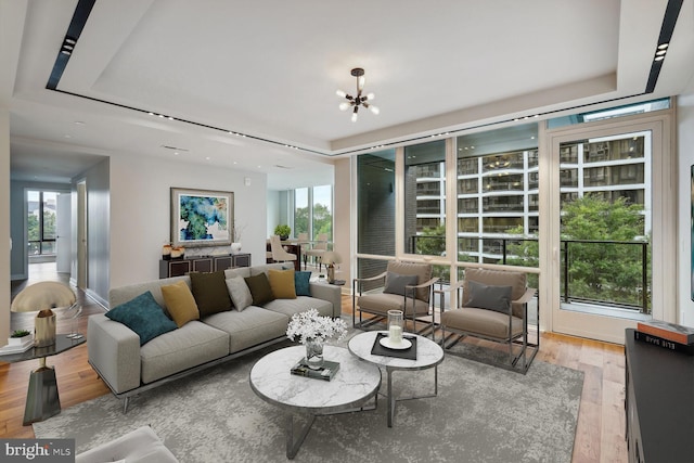 living area with a tray ceiling, wood finished floors, and an inviting chandelier