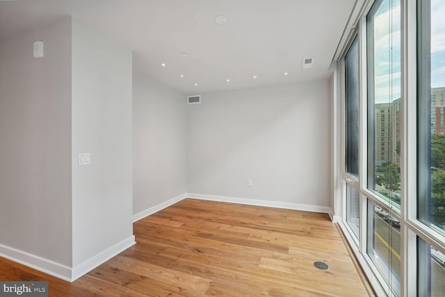 spare room featuring baseboards, a wealth of natural light, visible vents, and light wood-style floors