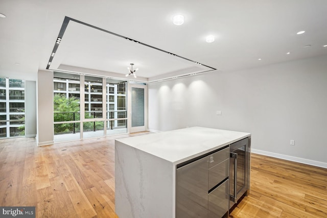 kitchen with open floor plan, light wood-type flooring, a kitchen island, and baseboards