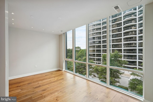 unfurnished room featuring baseboards, wood finished floors, and floor to ceiling windows