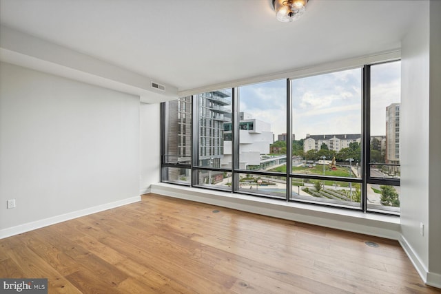 spare room with baseboards, a view of city, visible vents, and wood finished floors