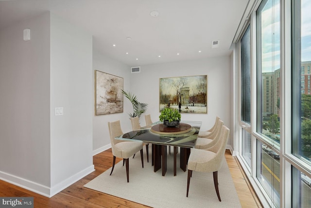 dining space with a wealth of natural light, visible vents, baseboards, and wood finished floors