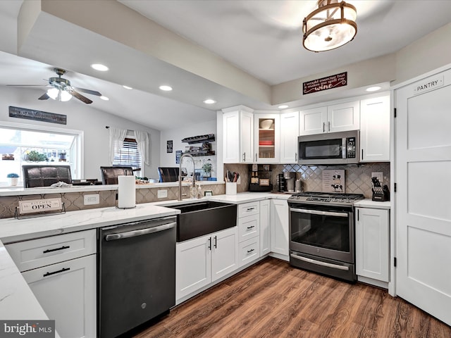 kitchen with tasteful backsplash, appliances with stainless steel finishes, dark wood-type flooring, white cabinetry, and a sink