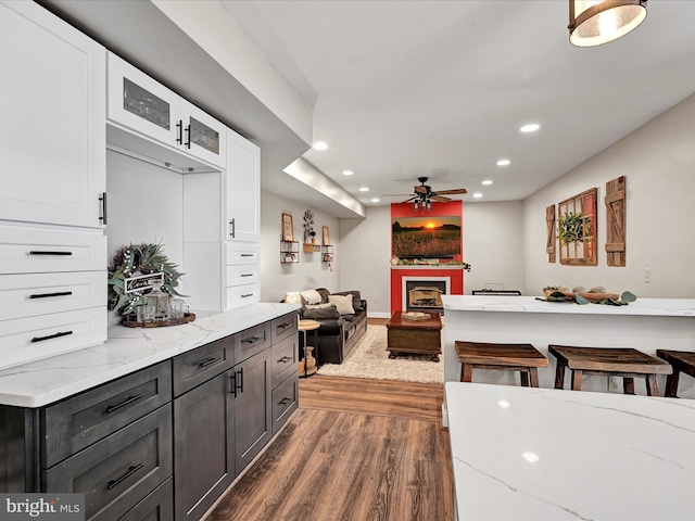 kitchen with light stone countertops, white cabinets, wood finished floors, and recessed lighting