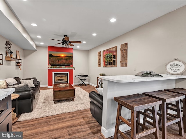 living area with recessed lighting, a fireplace, baseboards, and wood finished floors