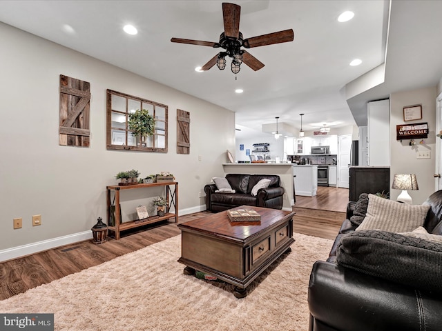 living room featuring baseboards, a ceiling fan, light wood-style flooring, and recessed lighting