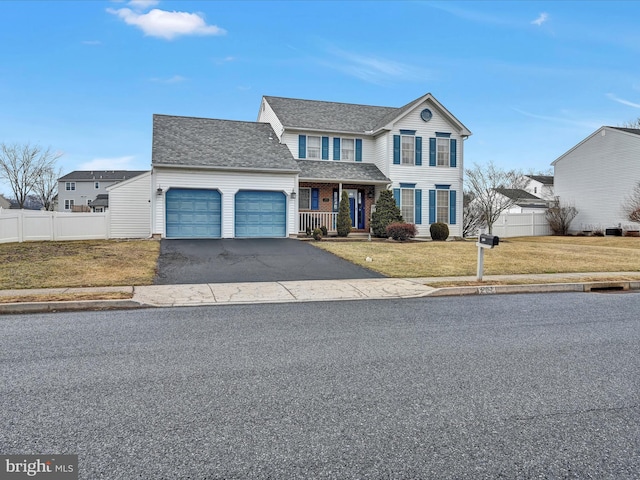 traditional-style home featuring driveway, an attached garage, fence, and a front lawn