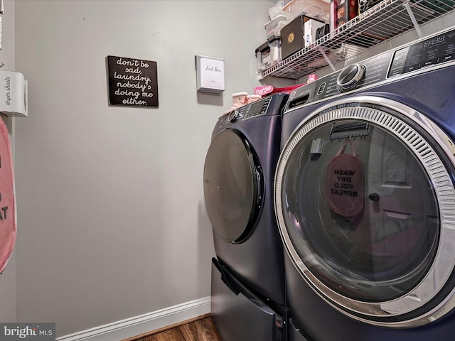 laundry area with washer and dryer, laundry area, baseboards, and wood finished floors