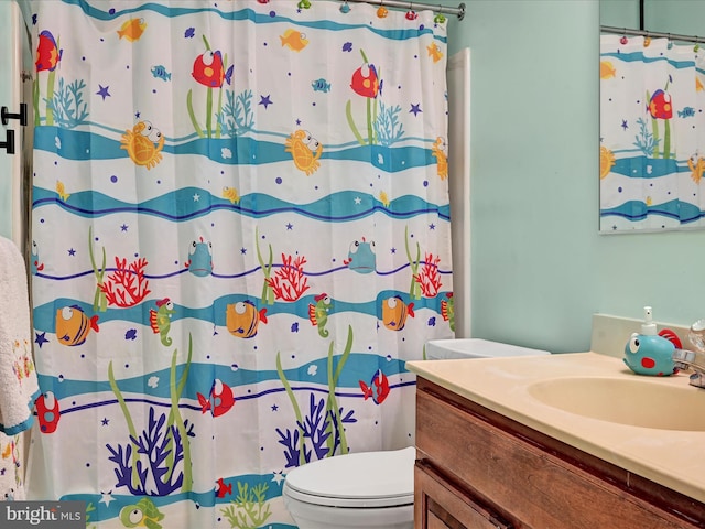 bathroom featuring toilet, a shower with shower curtain, and vanity