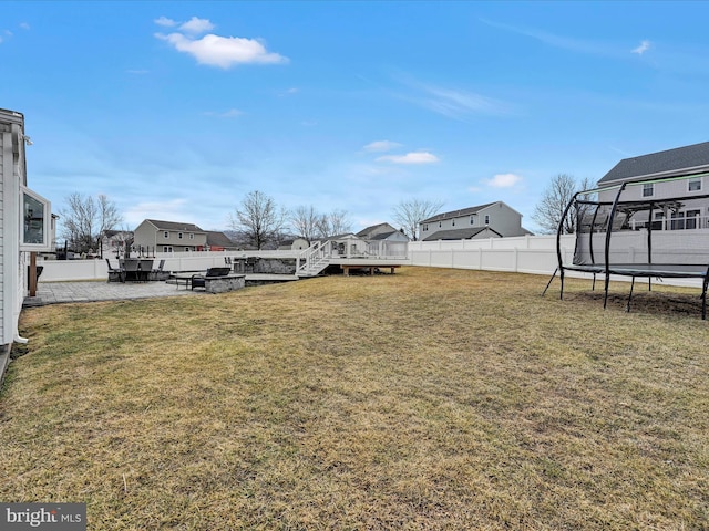 view of yard with a trampoline, a patio, a deck, a residential view, and a fenced backyard