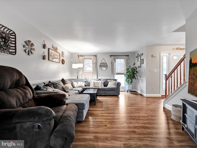 living area featuring dark wood-style floors, baseboards, and stairway