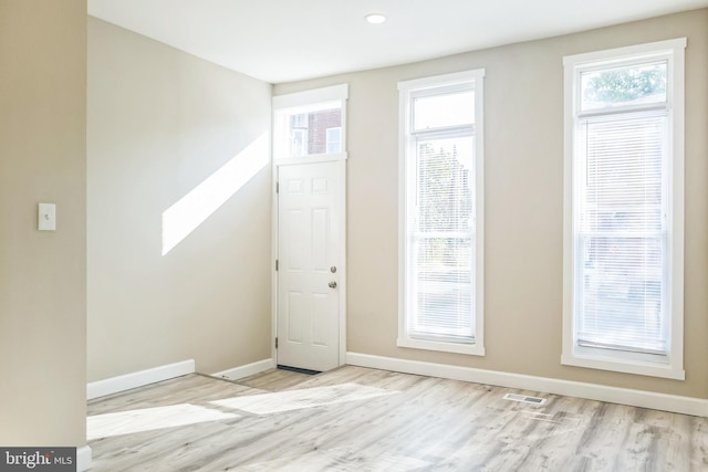 entrance foyer featuring a healthy amount of sunlight, visible vents, baseboards, and wood finished floors