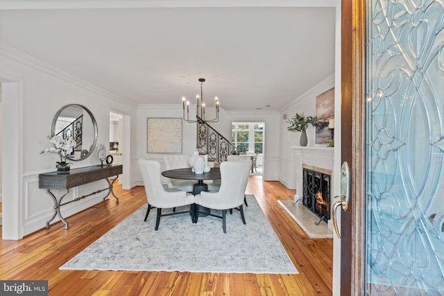 506 Ivy Cir, Alexandria, VA 22302 - dining room featuring an inviting chandelier, ornamental molding, a warm lit fireplace, french doors, and light wood finished floors