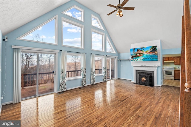 unfurnished living room featuring ceiling fan, wood-type flooring, a fireplace with flush hearth, and baseboards