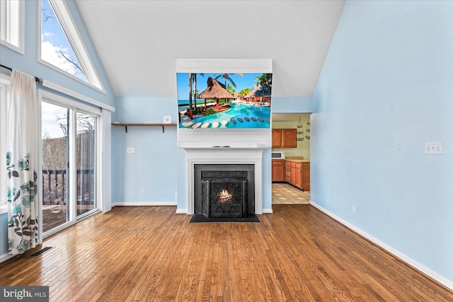 unfurnished living room featuring a fireplace with flush hearth, visible vents, high vaulted ceiling, and wood finished floors