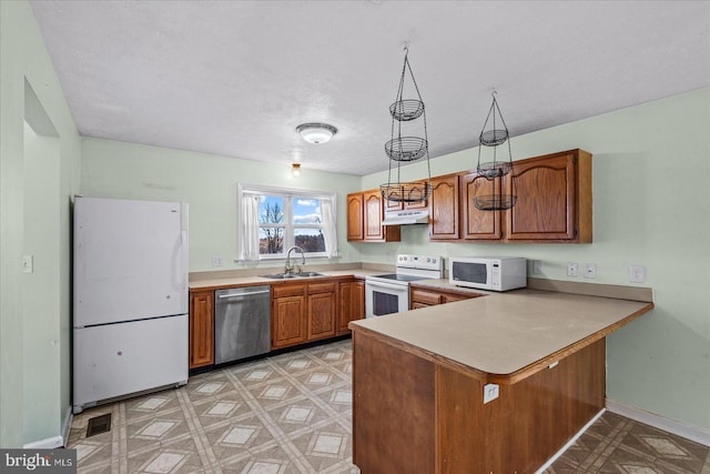 kitchen with light floors, a sink, a peninsula, white appliances, and under cabinet range hood