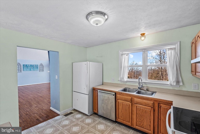 kitchen with a sink, light countertops, dishwasher, and freestanding refrigerator