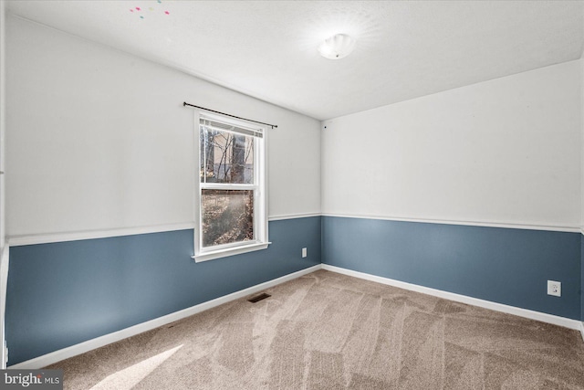 spare room with carpet floors, visible vents, and baseboards