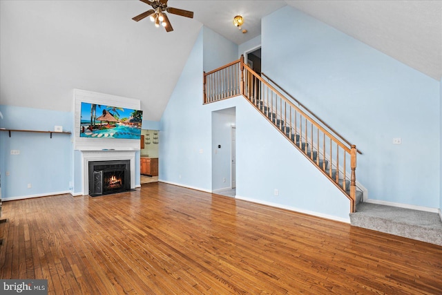 unfurnished living room featuring hardwood / wood-style flooring, a fireplace with flush hearth, stairs, and baseboards