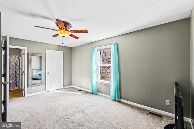 unfurnished bedroom featuring visible vents, carpet flooring, ceiling fan, a textured ceiling, and baseboards