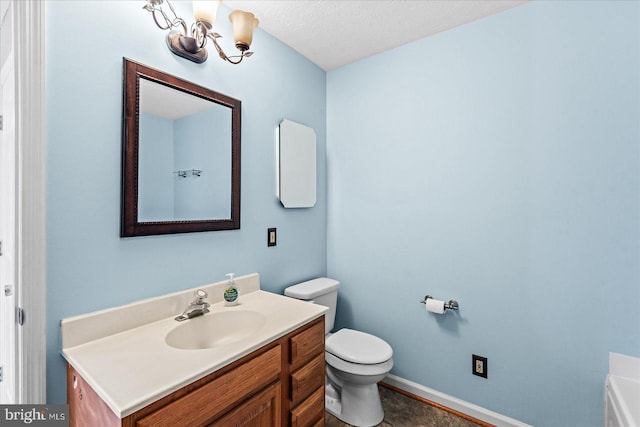 bathroom with baseboards, vanity, toilet, and an inviting chandelier