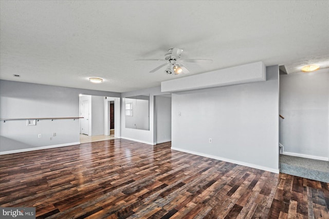 unfurnished living room with a textured ceiling, stairway, baseboards, and wood finished floors