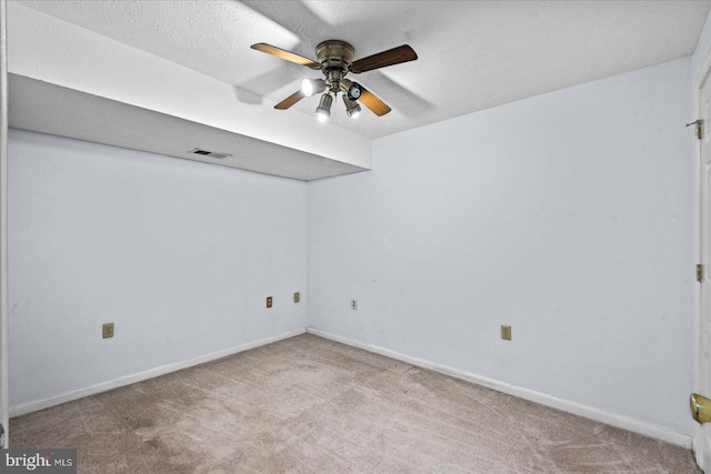 empty room with carpet, visible vents, ceiling fan, a textured ceiling, and baseboards