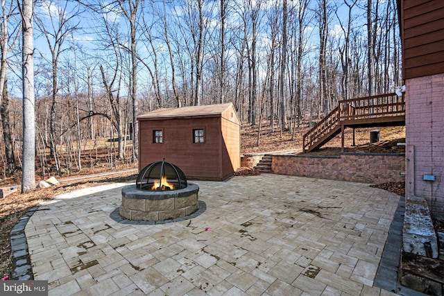 view of patio / terrace with stairway, an outdoor fire pit, a deck, a shed, and an outdoor structure