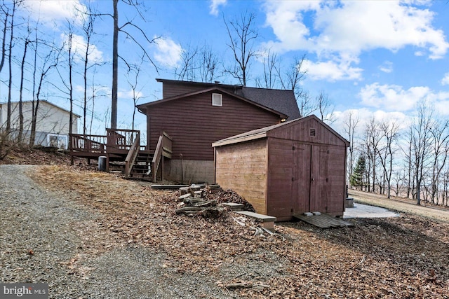 view of side of home with stairway, an outdoor structure, a deck, and a shed